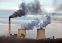 Massive EPA Rollback Sparks Lawsuit Frenzy Industrial power plant with smokestack and cooling towers emitting smoke