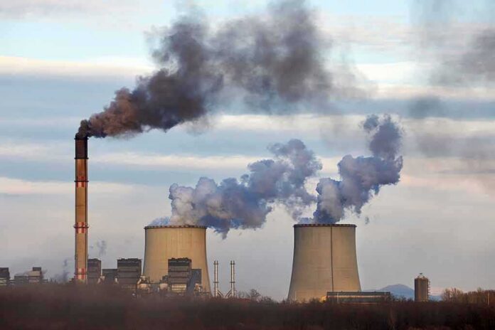 shutterstock_1555865300 Industrial power plant with smokestack and cooling towers emitting smoke