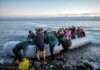 Group of people arriving on a crowded inflatable boat at a rocky shore