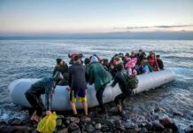 Group of people arriving on a crowded inflatable boat at a rocky shore