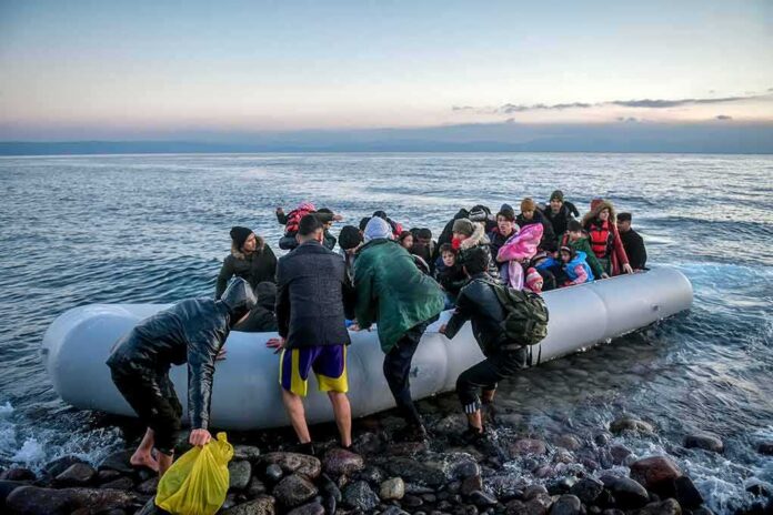 shutterstock_1661385784 Group of people arriving on a crowded inflatable boat at a rocky shore