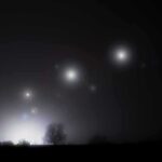 Pentagon Drops More UAP Bombshells Night sky over a silhouetted landscape with glowing orbs of light