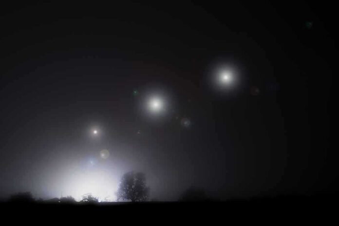 shutterstock_2239085913 Night sky over a silhouetted landscape with glowing orbs of light