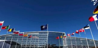 NATO headquarters with member flags in front under a clear blue sky