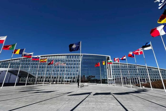 shutterstock_2284120437 NATO headquarters with member flags in front under a clear blue sky