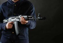Midnight Convoy Triggers Terror Scare person holding a rifle against a dark background