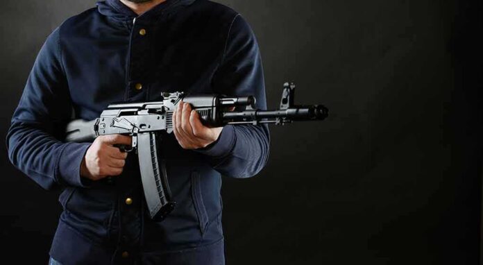 person holding a rifle against a dark background