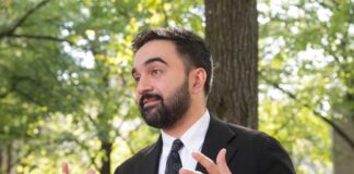 Man in a suit gesturing while speaking outdoors