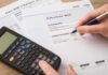 hand reviewing utility bills with calculator on desk