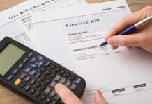 Electric Bills Climb – The Twist Nobody Admits hand reviewing utility bills with calculator on desk