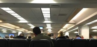 People seated in a waiting room with rows of chairs