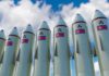 IAEA Alarm: North Korea Ramps Enrichment Row of missiles with flags and radiation symbols against a cloudy sky