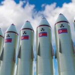 IAEA Alarm: North Korea Ramps Enrichment Row of missiles with flags and radiation symbols against a cloudy sky