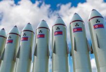 IAEA Alarm: North Korea Ramps Enrichment Row of missiles with flags and radiation symbols against a cloudy sky