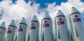 Row of missiles with flags and radiation symbols against a cloudy sky