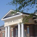 Backlash Erupts Over $6.4M Antisemitism Plan Exterior view of a city hall building with columns and a clear blue sky