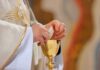 Priest’s Claim Sparks Communion Uproar Priest holding a communion wafer over a gold chalice