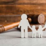 Agency Dangles Tri-Parent Adoptions Paper cutout family with gavel in background