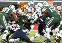 Football players collide in a heavy tackle at the line of scrimmage