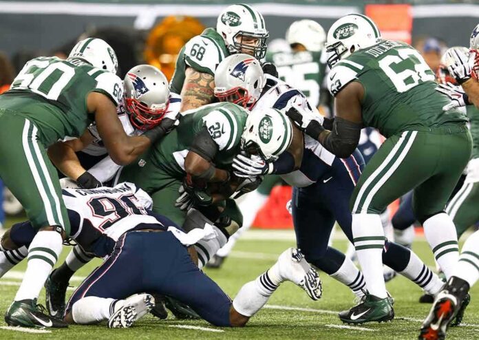 Football players collide in a heavy tackle at the line of scrimmage
