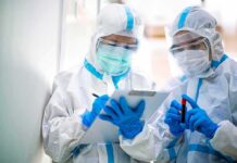 Kenya Confirms Ninth Ebola Case Inside Quarantine Two healthcare workers in full PPE reviewing a clipboard