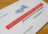 One-Day Stand-Down Shocks Military Mail-in ballot envelope with red label on wooden table