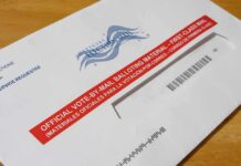 One-Day Stand-Down Shocks Military Mail-in ballot envelope with red label on wooden table