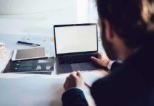 Person working at a laptop with blank screen on a desk