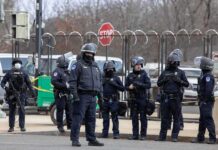 British Base Scare – Tehran Named Group of police officers in riot gear standing on a street; Brian Folkerts present