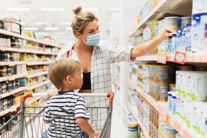 Woman wearing mask shops with child in grocery aisle