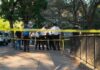 Philadelphia Shootout Leaves Officers Down Police officers gather behind yellow tape on a tree-lined sidewalk