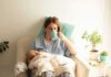 Mother nursing baby while drinking from a mug in a cozy chair