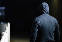 person in a dark hoodie walking at night