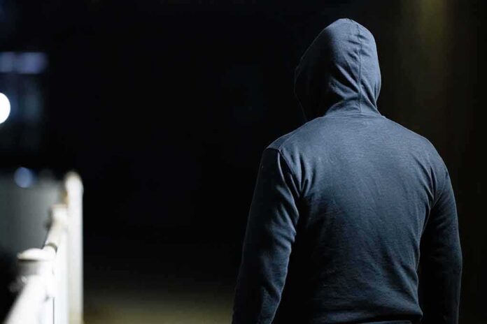 person in a dark hoodie walking at night
