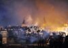 Riot police gather amid smoke at night