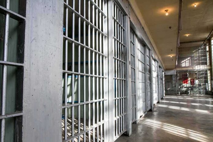 shutterstock_376750576-1 Prison cell block with metal bars and corridor