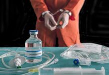 Lawyer Details Repeated IV Failures During Pike Execution Handcuffed person in orange jumpsuit behind medical vials and IV equipment
